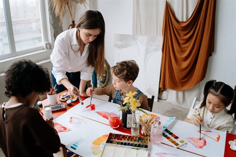 children painting with teacher helping.jpeg