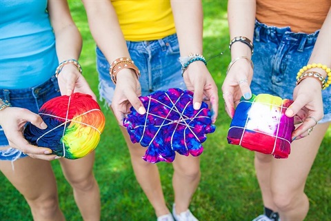 hands holding tie dyed shirts.jpeg